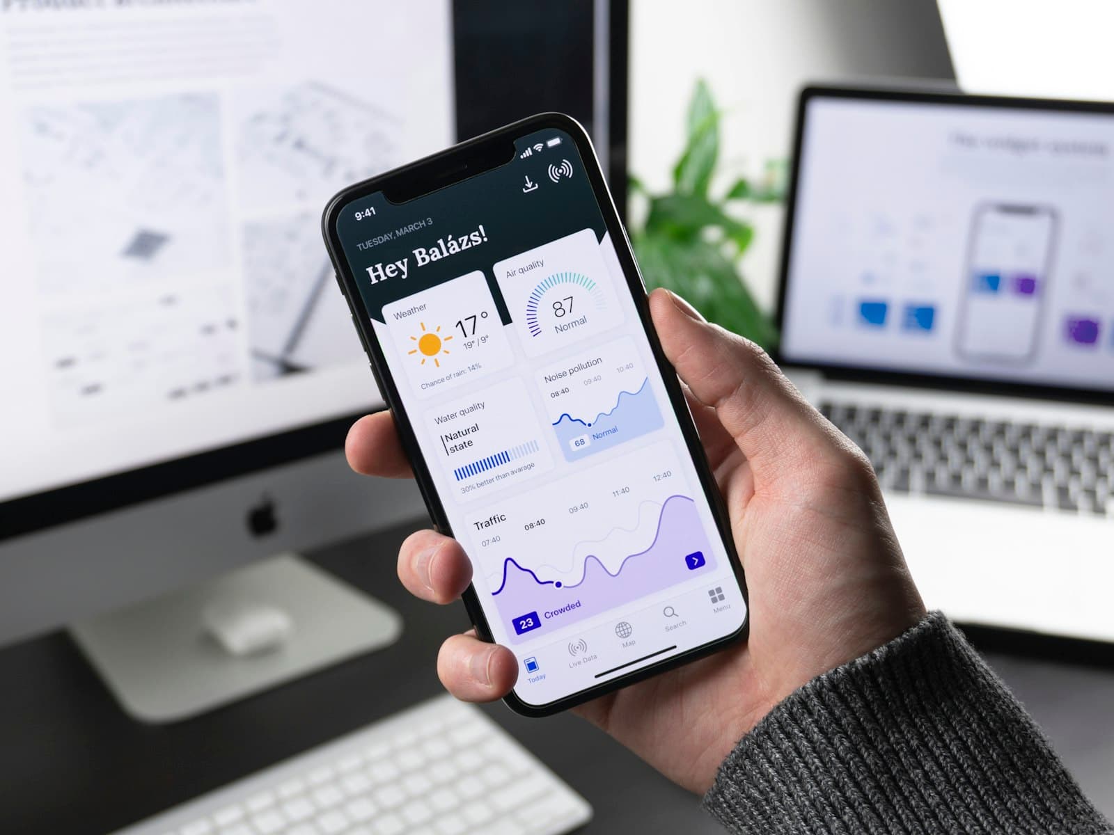 Hand holding a phone showing a finance app dashboard